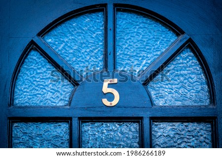House door number 5 on a  dark wooden front door with glass