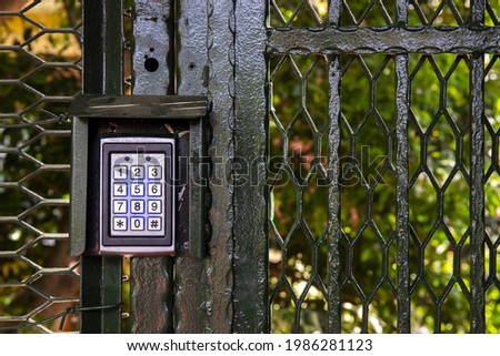 Secure password on keyboard for opening door. Metal code combination lock. Background of trees in the park. Royalty-Free Stock Photo #1986281123