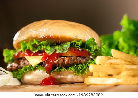 Beef and Cheese Burger in a brown background. Tasty homade hamburger mix with french fries, union and salad. Side view Royalty-Free Stock Photo #1986286082