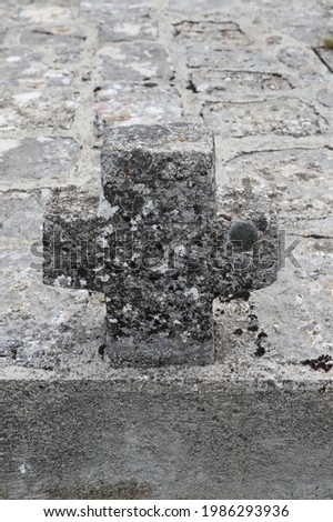 Stone cross as a tombstone on the tomb in front of the Catholic church