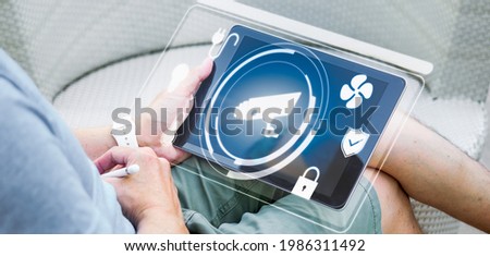 Man using tablet computer to control Smart home as automation assistant. Panoramic banner of Futuristic house ideas