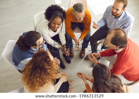 Patients talking in group therapy feeling connected, safe and supported. Diverse people trying to understand each other in friendly positive atmosphere of psychotherapy session. High angle, from above Royalty-Free Stock Photo #1986313529