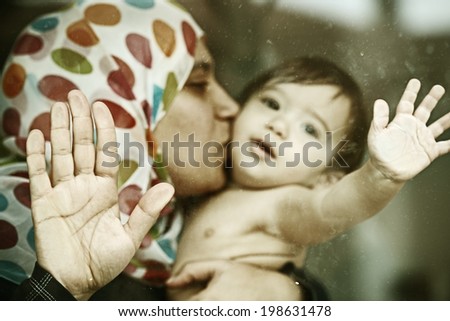 Baby on window glass with mother Royalty-Free Stock Photo #198631478