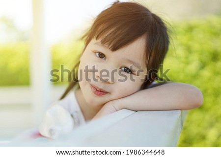 Close-up of a happy smiling girl's face in the backyard in the bright morning atmosphere. beautiful face of Asian girls