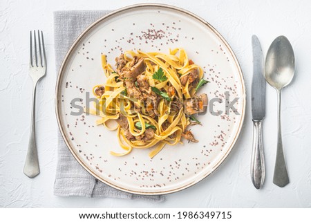 Braised rabbit with rosemary, garlic and pasta tagliatelle or pappardelle set, on plate, on white stone  background, top view flat lay