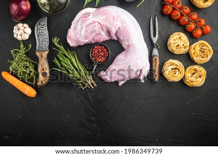 Raw whole  rabbit with fresh vegetables and pasta for rabbit  stew set, on black stone background, top view flat lay, with copy space for text