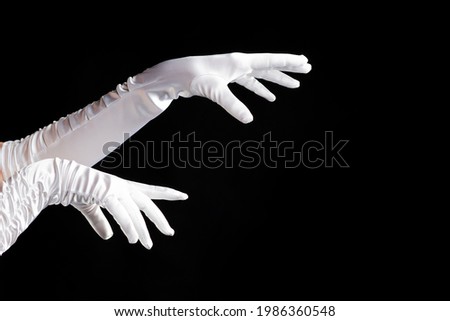 Hand gestures. lady in long white gloves points to the side, a show of magic. black background.