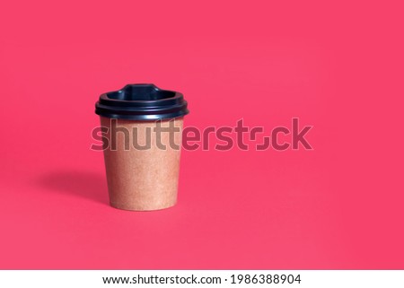 Cardboard coffee cup with lid on a red background with place for text. The concept of ecological packaging in a modern coffee shop. Disposable coffee cup