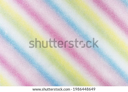 Background covered with glitter in diagonal lines in different colors of the rainbow, top view.