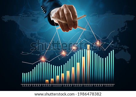 The puppeteer's male hand manipulates financial charts, business indicators. The concept of shadow government, world conspiracy, manipulation, control Royalty-Free Stock Photo #1986478382
