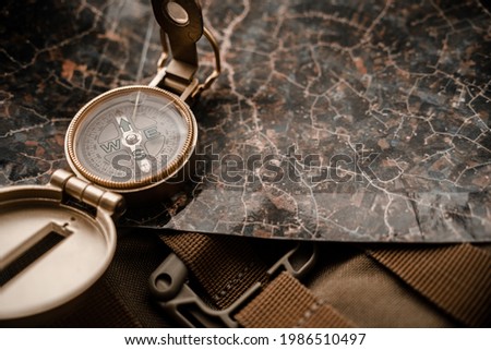 golden compass on tactical or travel backpack, shallow DOF, focus on dial. Concept for direction, travel, guidance or assistance. Selective focus.