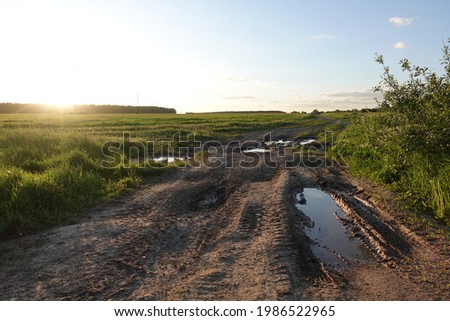 Rut dirt road across steppe after rain against sunset sky background. Russia Royalty-Free Stock Photo #1986522965
