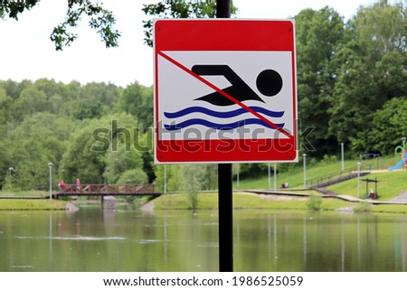 Forbidding swimming sign on background of summer lake. Beach holiday in city park