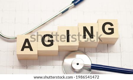wooden block form the word aging with stethoscope on the doctor's desktop. healthcare conceptual for hospital, clinic and medical business.