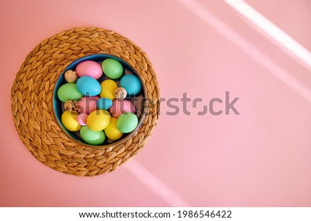 Colorful easter eggs in bowl, pink background