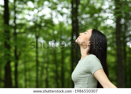 Side view portrait of an asian woman breathing fresh air in a forest Royalty-Free Stock Photo #1986550307