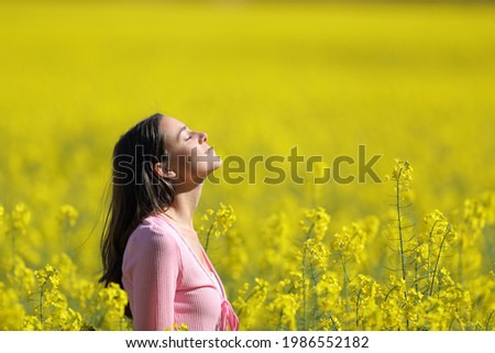Profile of a relaxed woman breathing deeply fresh air in a yellow field in spring season Royalty-Free Stock Photo #1986552182