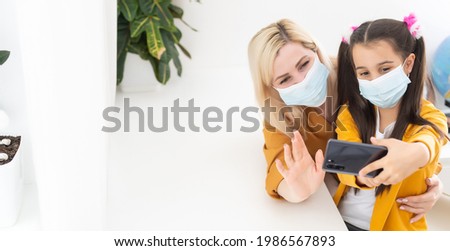 mother and little daughter take a selfie in masks