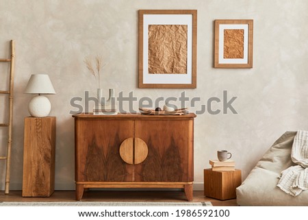 Interior design of neutral living room with stylish retro commode, mock up poster frame, cube, table lamp, decoration and elegant personal accessories in home decor. Template. Japandi concept. Royalty-Free Stock Photo #1986592100