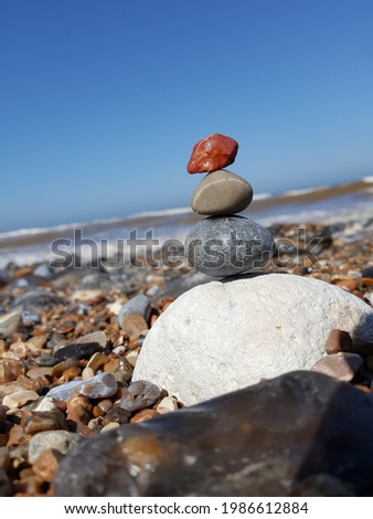 Coloured stones balanced on top of each other with sand and sea of beach in the background