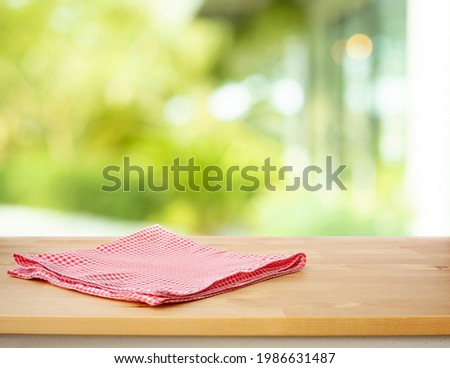 Red checked tablecloth on wood with blur green garden background.Design for key visual food and drink products.