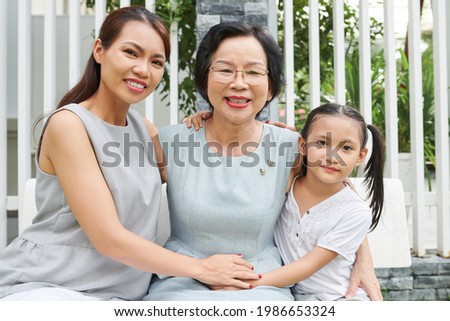 Portrait of happy senior woman enjoying spending time with daughter and granddaughter visiting her at home on birthday