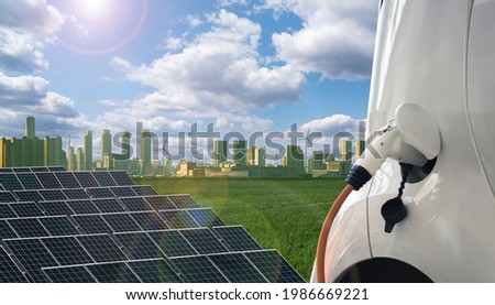 Close up of electric car with a connected charging cable on the background of green eco city Royalty-Free Stock Photo #1986669221
