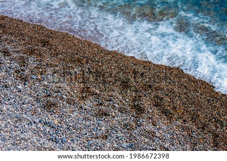 Pebbled gray beach and sea surf with white foam