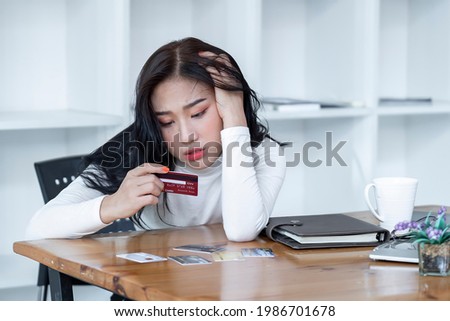 Stressed young woman while holding credit card with feeling stressed and broke, Desperate woman with credit card debt, Income is not enough for expenses. Work from home