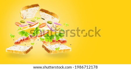 In the photo we see a sandwich in a state of levitation. Sandwich pictured in the left corner. Pastel light colors. Pale yellow background. High angle view. There is a place for your insert.