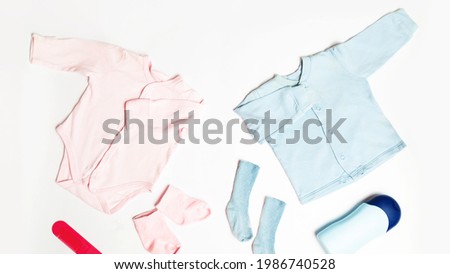 Clothes and accessories for newborn. Pregnancy and preparation for childbirth. Shirt, bodysuit, socks, toy. White table background. Flat lay. Top view. copy space