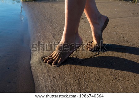 a girl walks on the sandy shore with bare feet on the sand and the beach, feet are on the sand
