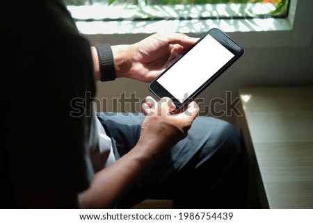 Close up view of man sitting on sofa and using mobile phone. Blank screen for advertise text.	