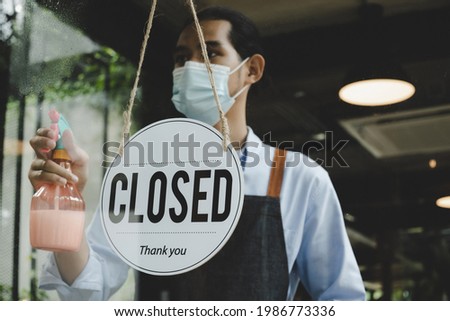 Closed. vintage sign board hanging on glass door with waitress staff wearing protective face mask cleaning and washing mirror window in cafe coffee shop restaurant, small business owner concept