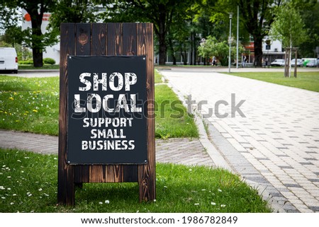Shop Local. Support small business. Wooden billboard on the street, sunny day. Royalty-Free Stock Photo #1986782849