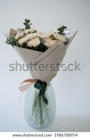 Bouquet of white flowers in a glass vase on a white background