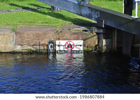 Close Up of Partly Submerged 'Keep Clear of Cill' Sign on Wall of Industrial Canal