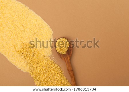 Organic Hulled millet flour and Heap grain on beige background. Top view, space for text.