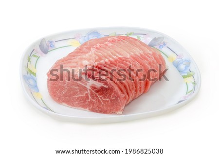 Sliced raw partly frozen pork loin on dish on a white background 
