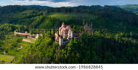 Panoramic, aerial view of ancient royal Moravian castle Pernstejn with new Vrchnostenska garden, illuminated by sun against dark forest. Aerial photography. Bohemian-Moravian Highlands, Czech castles