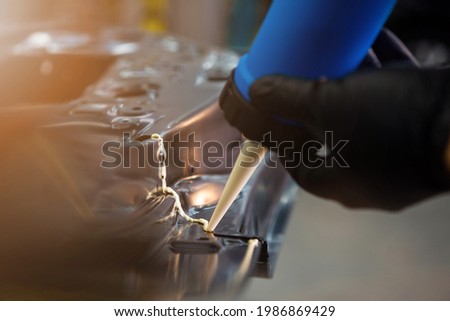 A man applies sealant to the car door. Repair and install auto doors with silicone rubber, car plant. auto service. automobile concept Royalty-Free Stock Photo #1986869429
