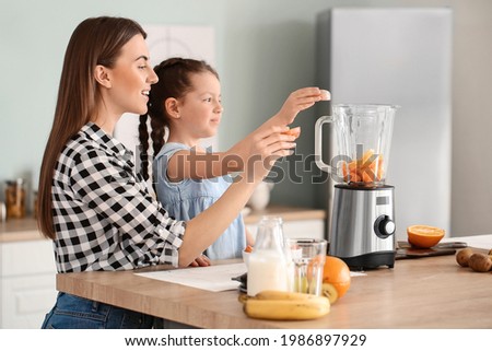 Mother and little daughter making healthy smoothie in kitchen Royalty-Free Stock Photo #1986897929