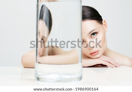 beautiful girl under glass bottle with water. clean skin young woman. Beauty Fashion Portrait