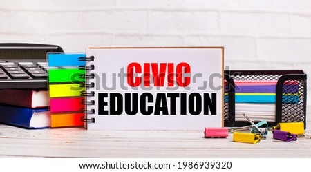 On a light wooden background, a calculator, multi-colored sticks and a notebook with the text CIVIC EDUCATION. Business concept