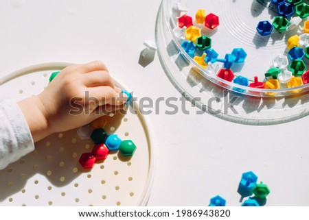 The toddler creates a multi-colored mosaic figure.