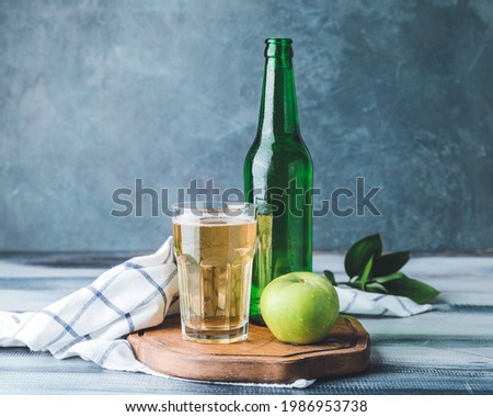 Bottle and glass of apple cider on table