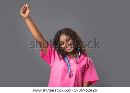 An African female doctor in a pink uniform raises her hands in triumph. optimism, victory of disease, epidemic