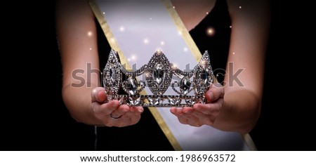 Prize Winning Award for Winner of Miss Beauty Queen Pageant Contest is Sash, Diamond Crown, studio lighting abstract dark draping textile background Royalty-Free Stock Photo #1986963572