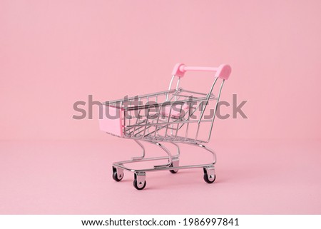 Small shopping market trolley on a pink background, copy space, shopping concept side view