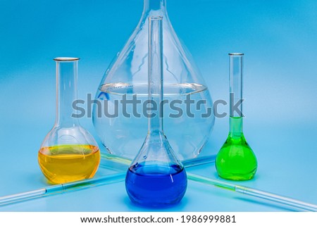 Four glass laboratory flasks with solutions of various colors on a gentle blue medical background. The concept of medical and chemical experiments. Close-up